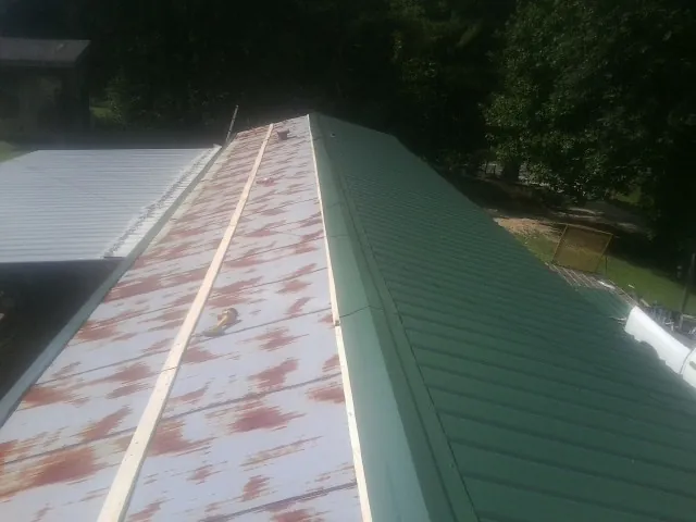 Old rusted panels beside newly installed green metal roofing — Wind Damage Roof Repair by Roofing Brothers in Jbsa Lackland
