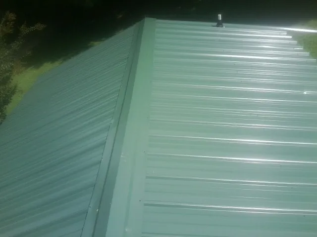 New green metal panels meeting at the ridge of a roof — Flat Roof Repair work by our crew in Jbsa Lackland