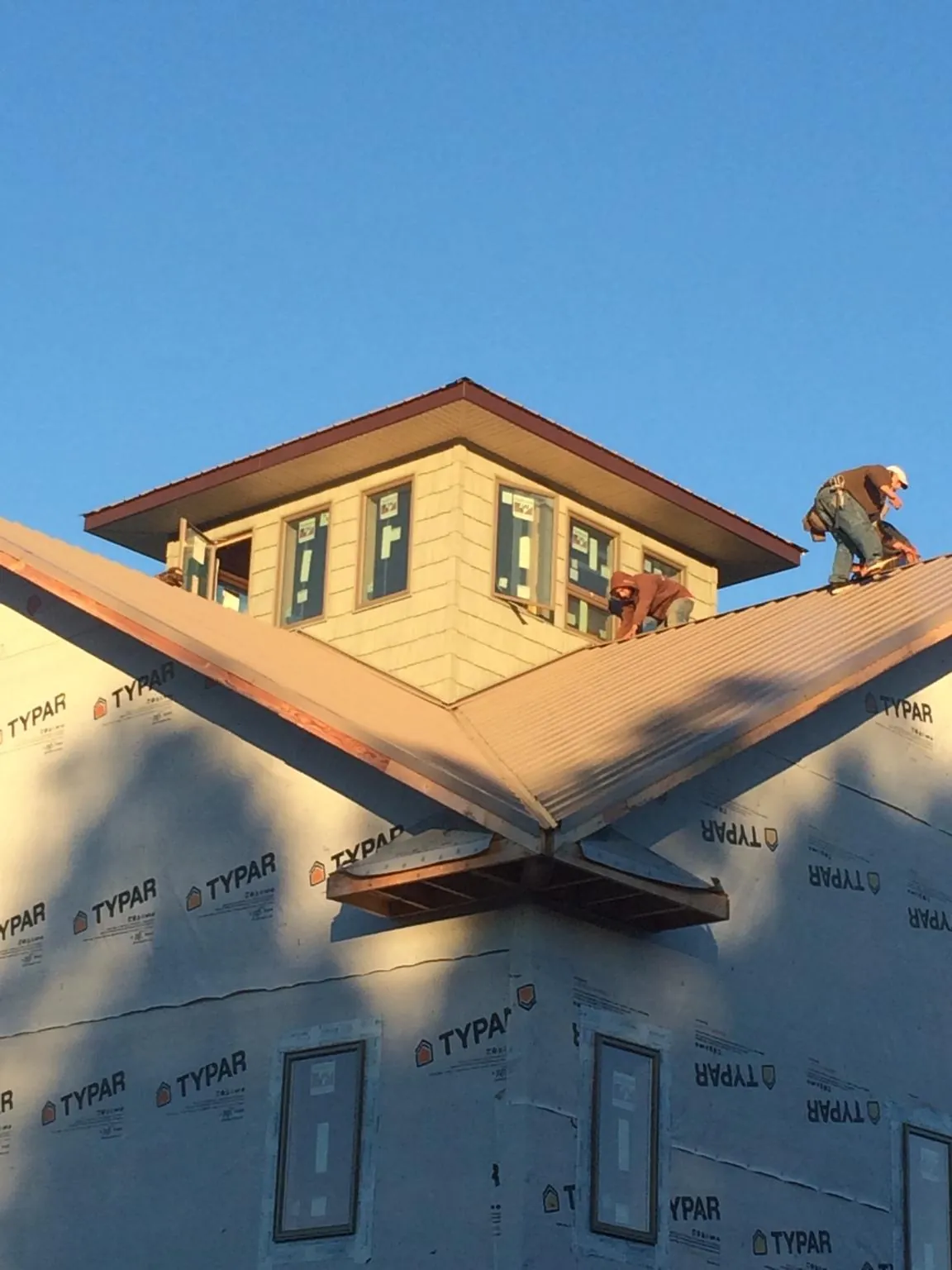 Roofers working around a rooftop cupola on a new metal roof at sunset — Roof Waterproofing in Jbsa Lackland by Roofing Brothers